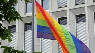 Regenbogenflagge am Mast vor dem Gebäude des BMI